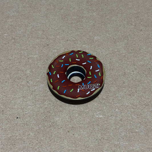 Donut-shaped object with sprinkles on a gray background